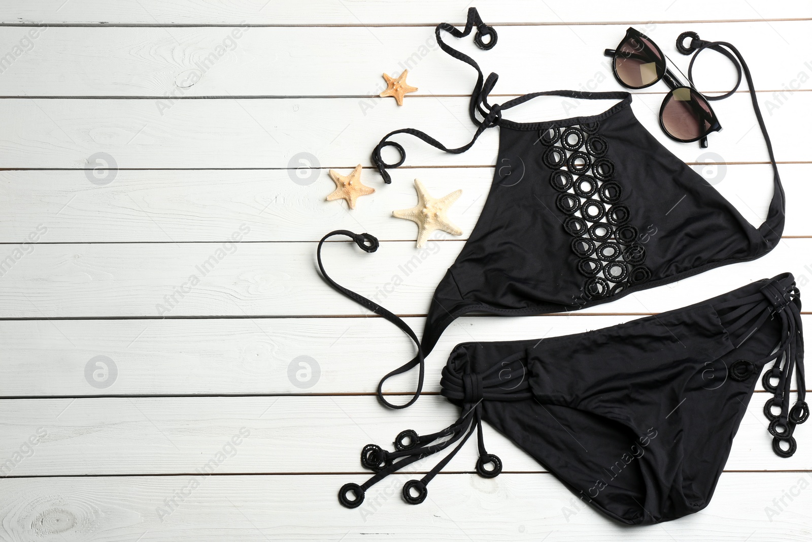 Photo of Swimsuit, sunglasses and starfishes on white wooden table, flat lay with space for text. Beach accessories