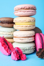 Pile of delicious colorful macarons on light blue background