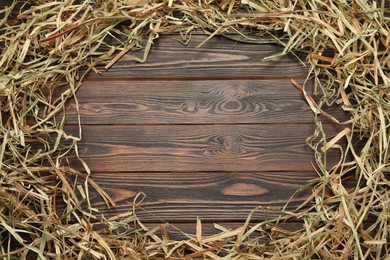 Photo of Frame made of dried hay on wooden background, top view. Space for text