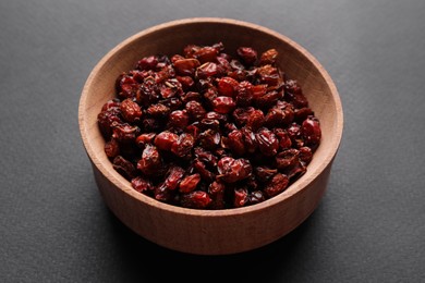 Photo of Dried barberries in wooden bowl on grey background