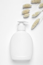 Bottle of cosmetic product and dry decorative spikes on white background, flat lay