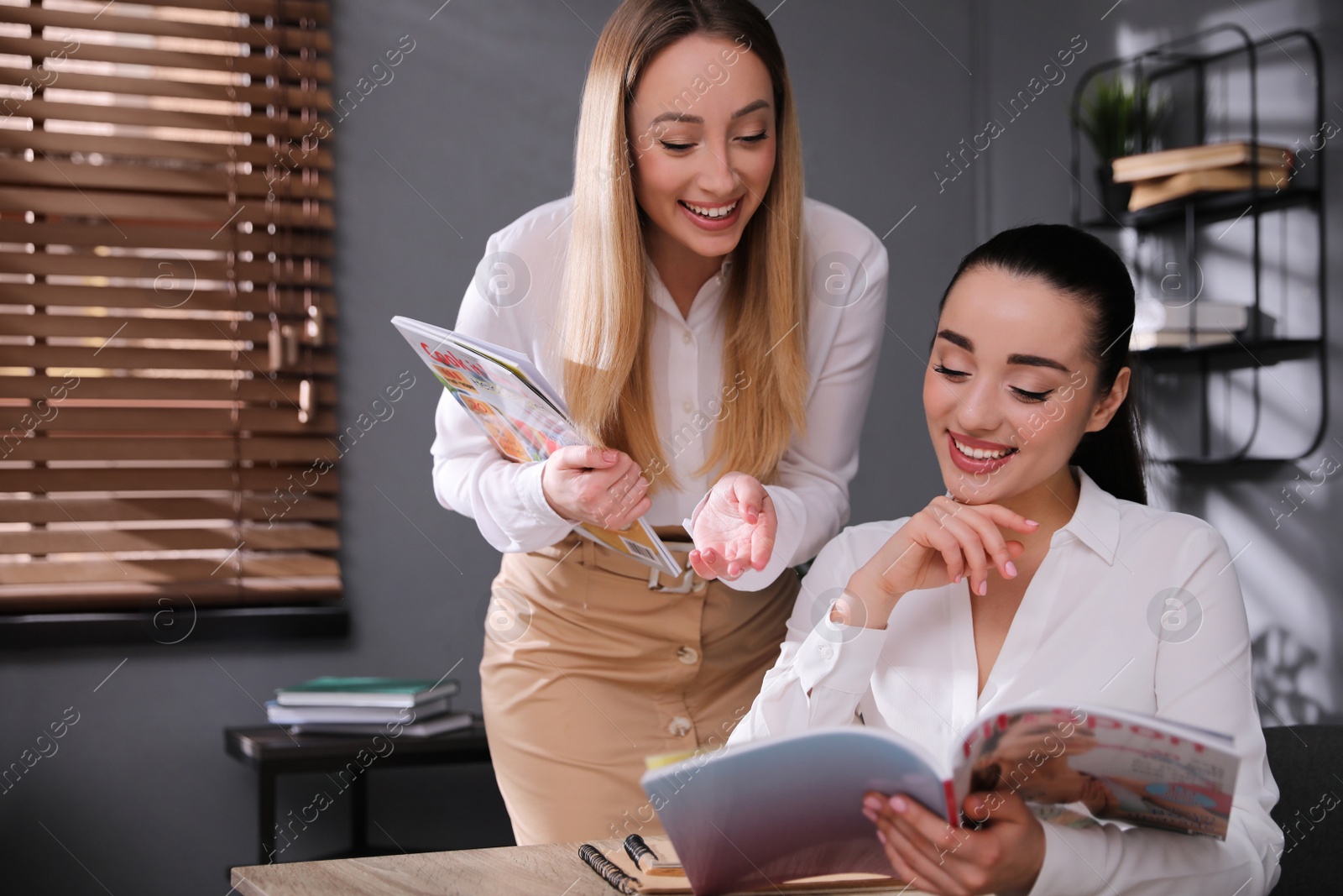 Photo of Happy young women with magazines in office