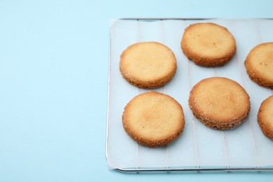 Photo of Tasty sweet sugar cookies on light blue background. Space for text