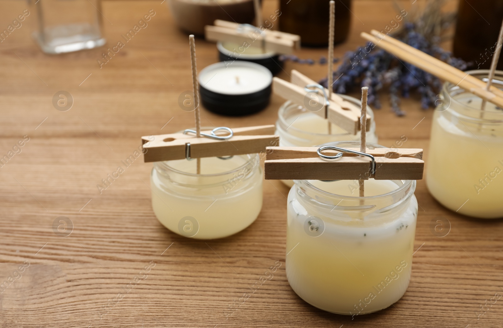 Photo of Glass jars with wax on wooden table, space for text. Handmade candles