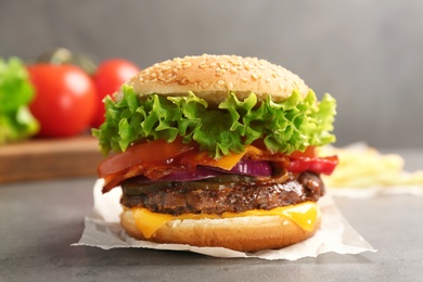 Photo of Tasty burger with bacon on grey table