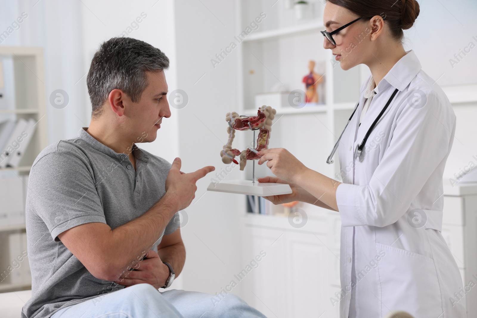 Photo of Gastroenterologist with anatomical model of large intestine consulting patient in clinic