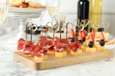 Different tasty canapes on white marble table, closeup