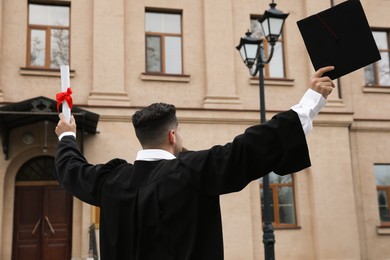 Photo of Student with diploma after graduation ceremony outdoors