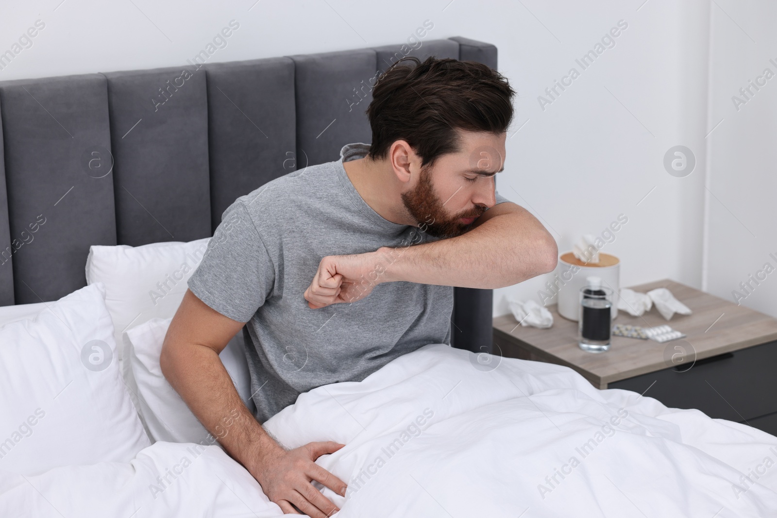 Photo of Sick man coughing on bed at home. Cold symptoms