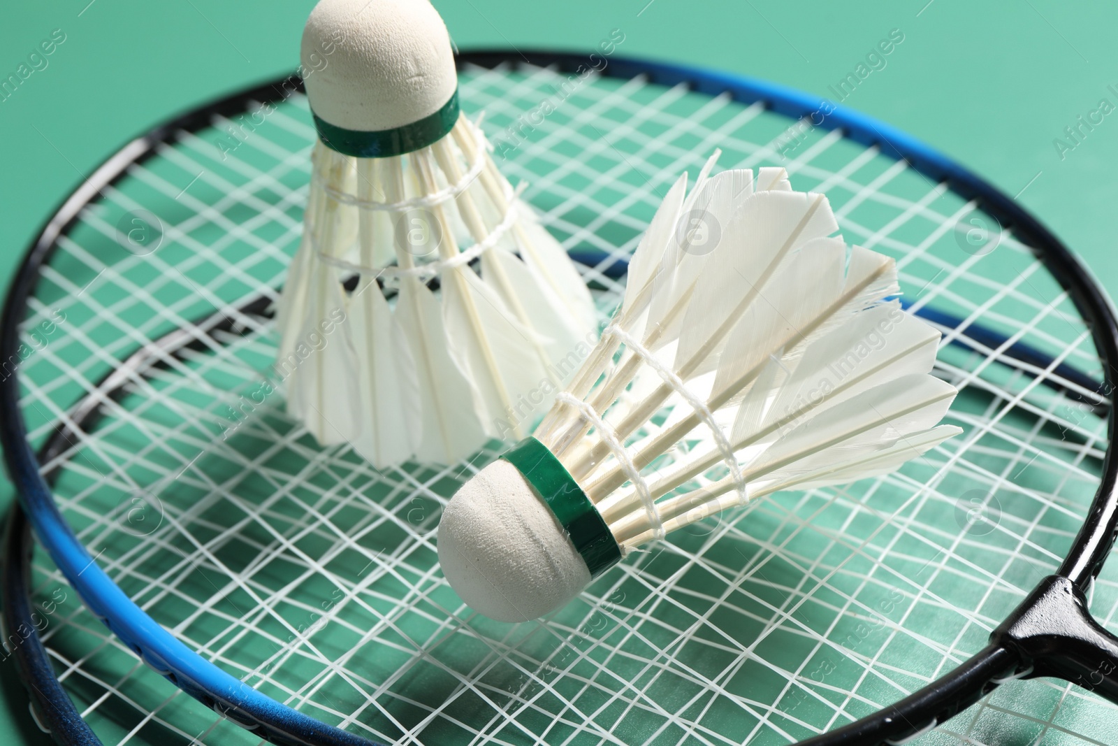 Photo of Feather badminton shuttlecocks and rackets on green background, closeup