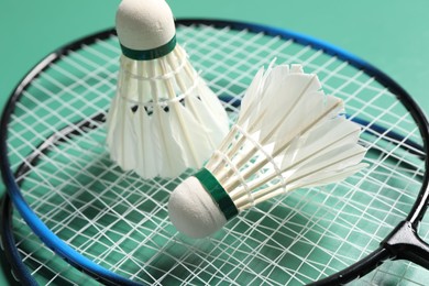 Feather badminton shuttlecocks and rackets on green background, closeup