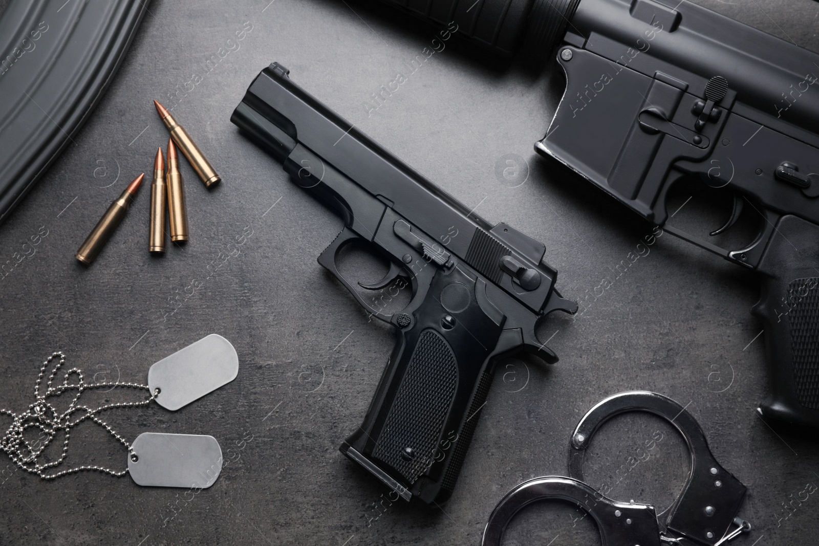 Photo of Composition with gun and bullets on stone table, flat lay