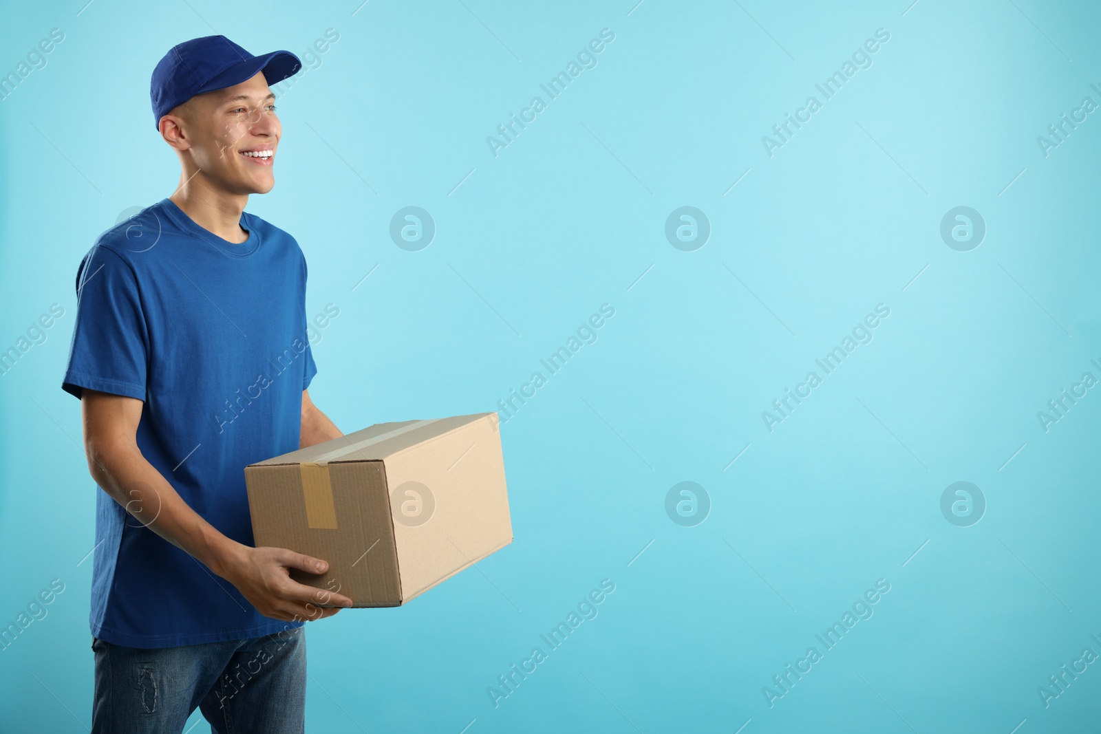 Photo of Happy courier with parcel on light blue background. Space for text