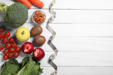 Photo of Measuring tape, almonds, fresh fruits and vegetables on white wooden table, flat lay with space for text. Low glycemic index diet