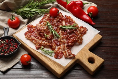 Photo of Slices of tasty fried bacon, tomatoes and different spices on wooden table, top view