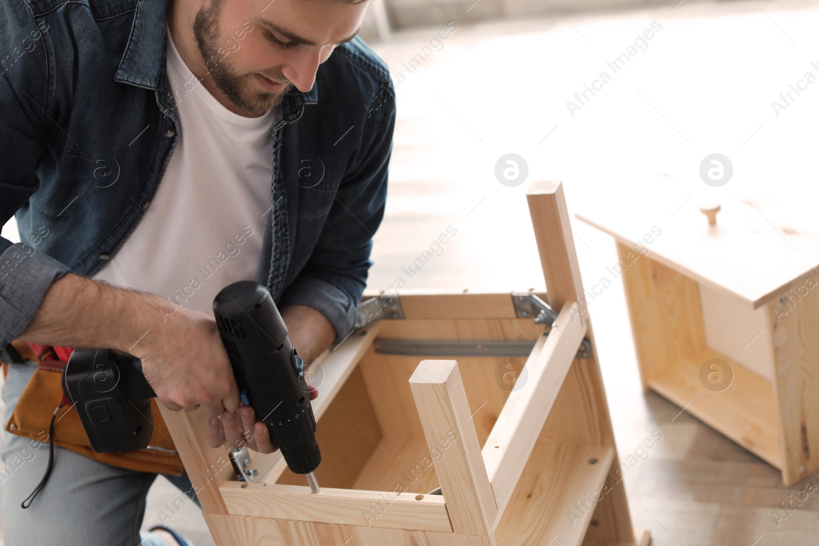 Photo of Young man working with modern electric screwdriver indoors