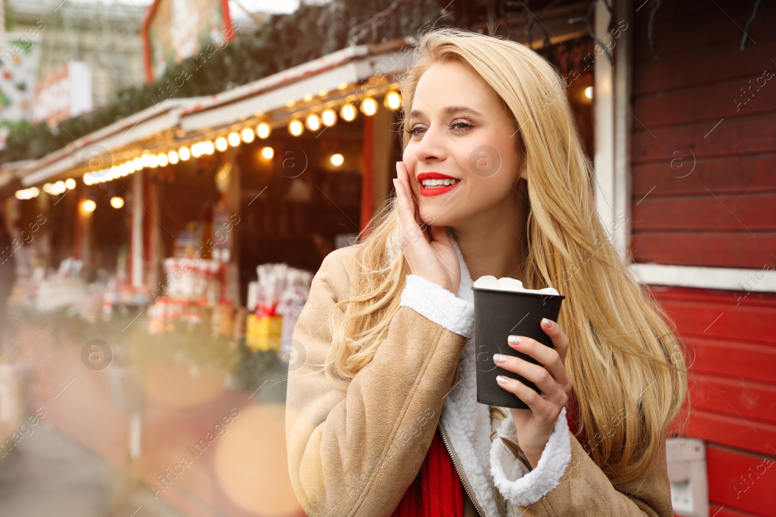 Photo of Young woman with hot drink at Christmas fair