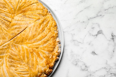 Traditional galette des rois on white marble table, top view. Space for text