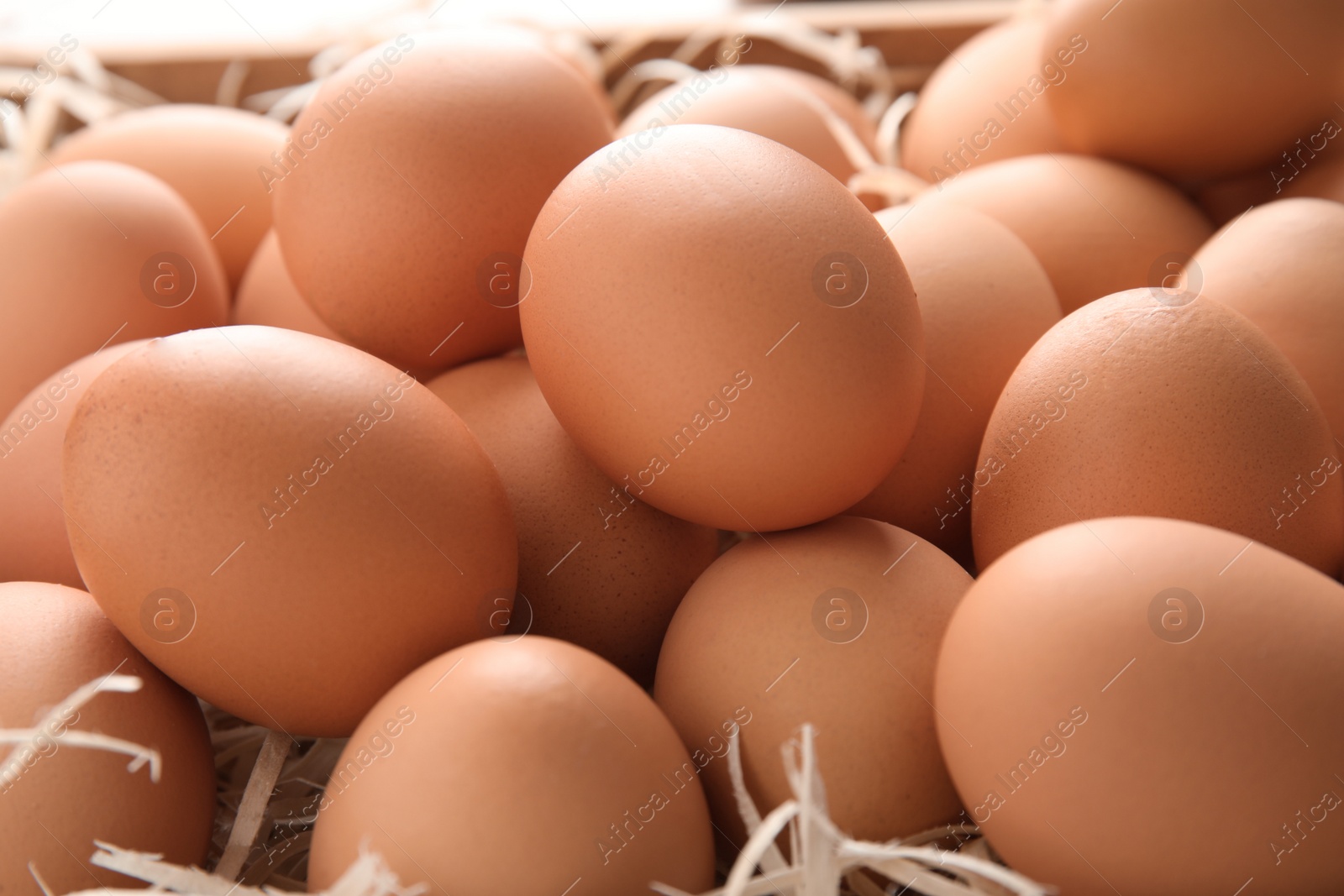 Photo of Pile of raw brown chicken eggs in straw