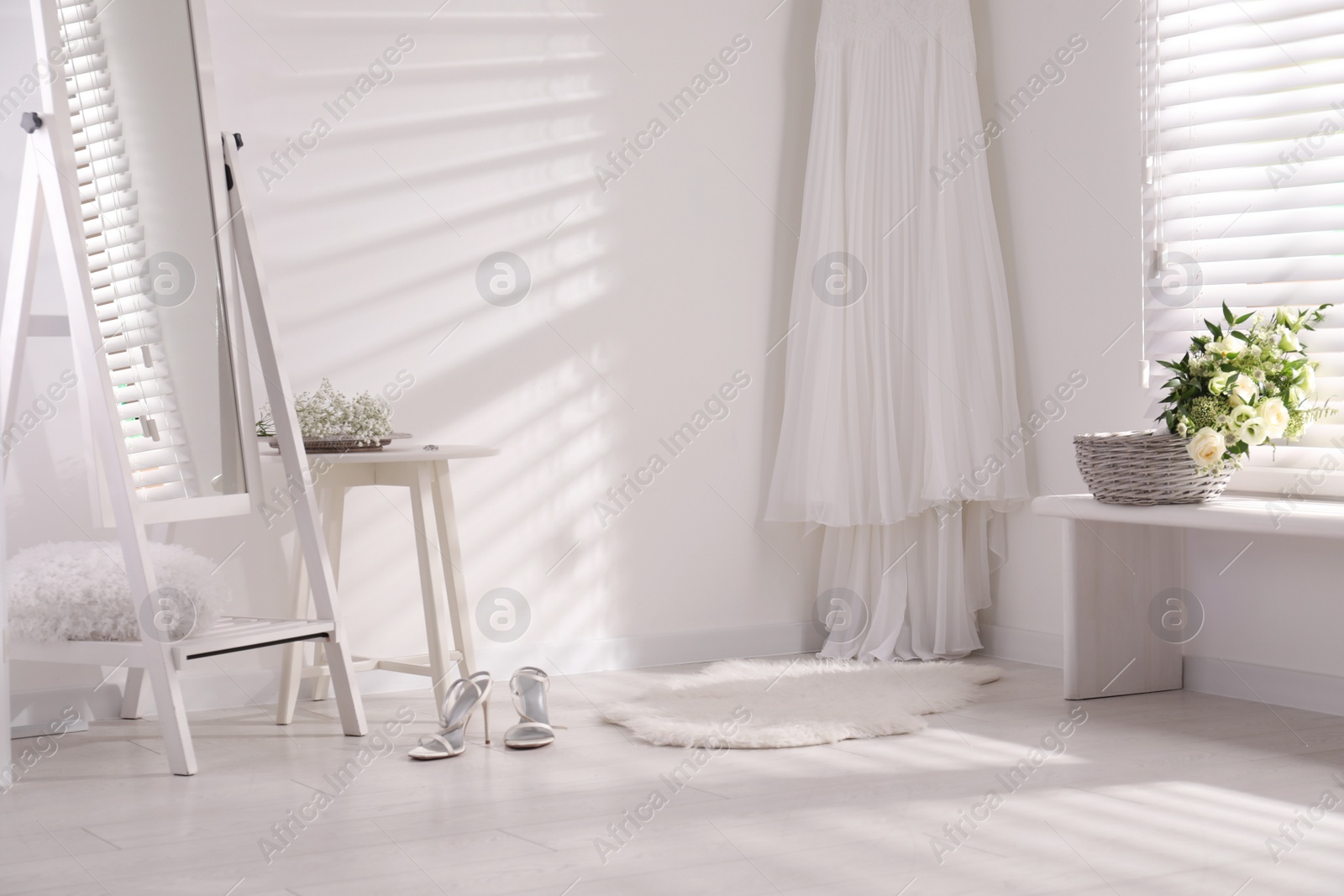 Photo of Beautiful wedding dress hanging on white wall in room