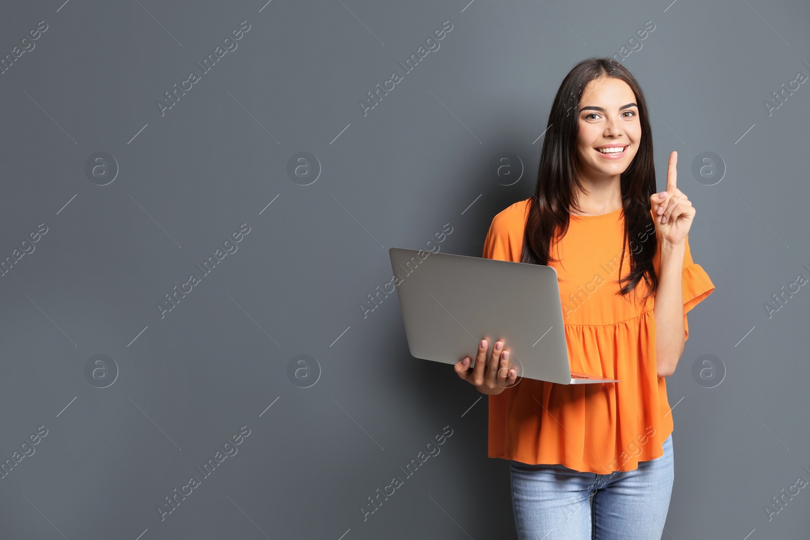 Photo of Young woman with modern laptop on grey background