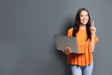 Photo of Young woman with modern laptop on grey background