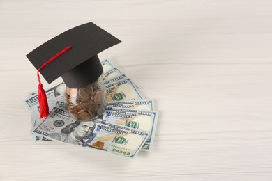 Scholarship concept. Graduation cap, coins and banknotes on white wooden table, space for text
