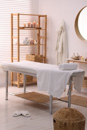 Comfortable massage table with clean towels in spa center