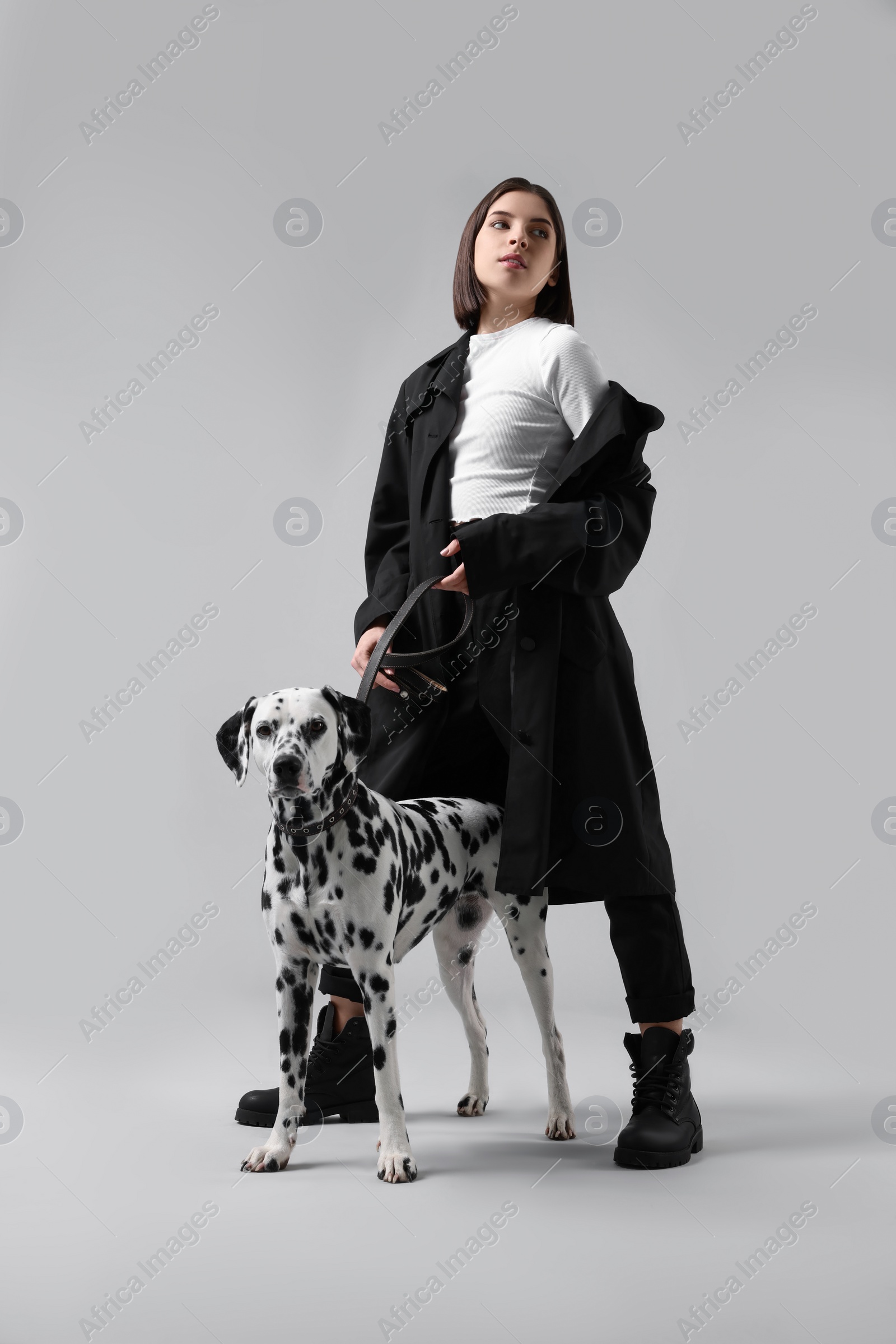 Photo of Beautiful young woman with her adorable Dalmatian dog on light grey background. Lovely pet