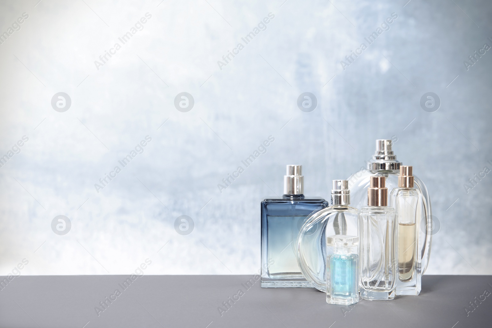 Photo of Different perfume bottles on table against color background