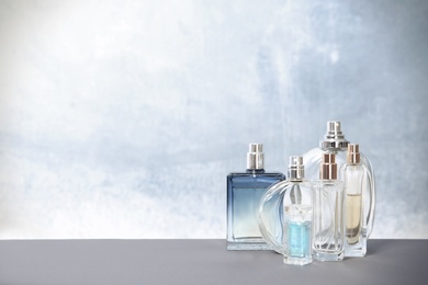 Different perfume bottles on table against color background