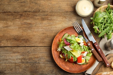 Photo of Delicious salad with lettuce served on wooden table, flat lay. Space for text