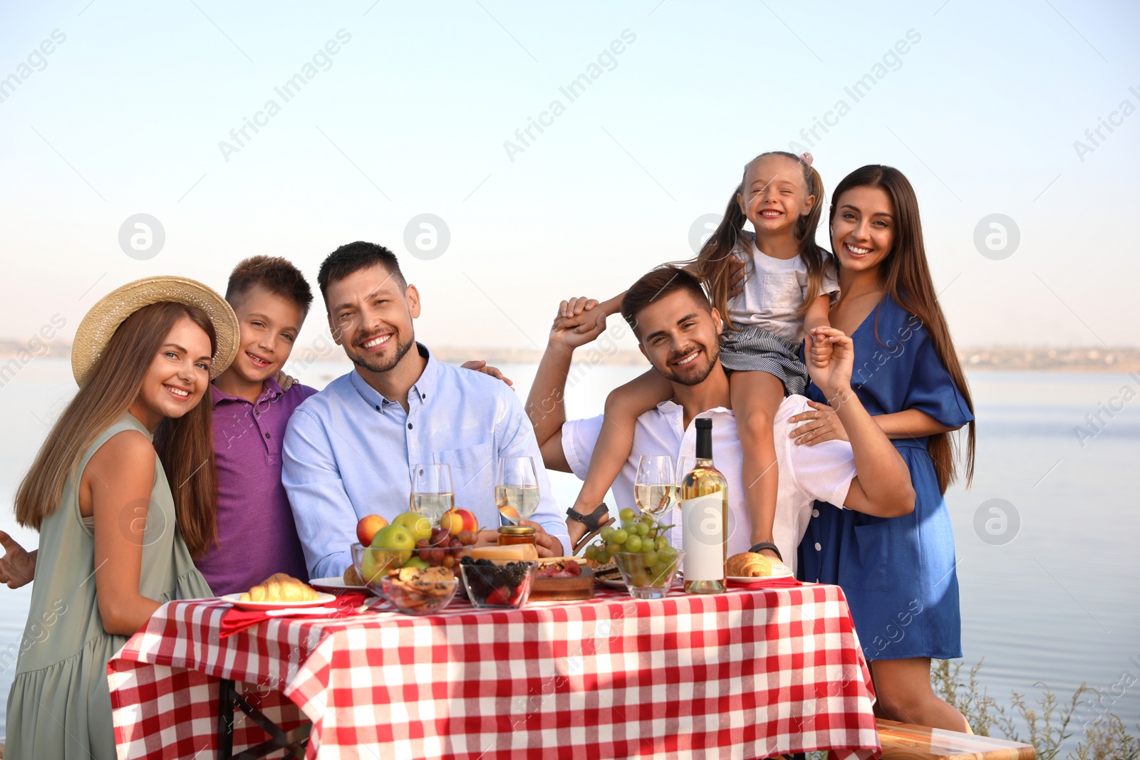 Photo of Happy families with little children having picnic at riverside