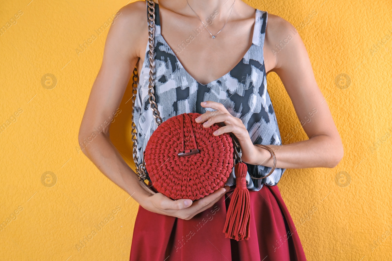 Photo of Young woman in stylish outfit with purse on color background, closeup