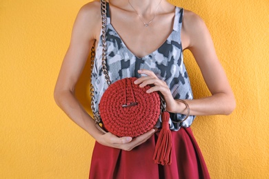 Young woman in stylish outfit with purse on color background, closeup