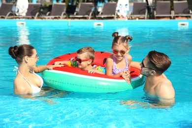 Young family with little children in swimming pool on sunny day