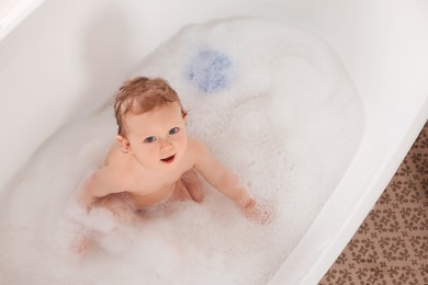 Cute little baby bathing in tub at home, top view