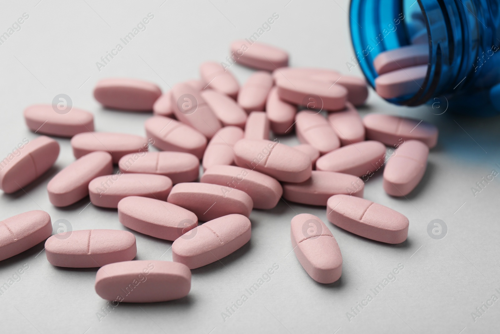 Photo of Vitamin pills and bottle on grey background, closeup