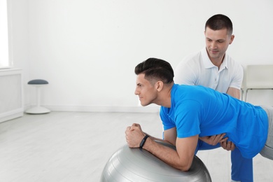 Professional physiotherapist working with male patient in rehabilitation center. Space for text