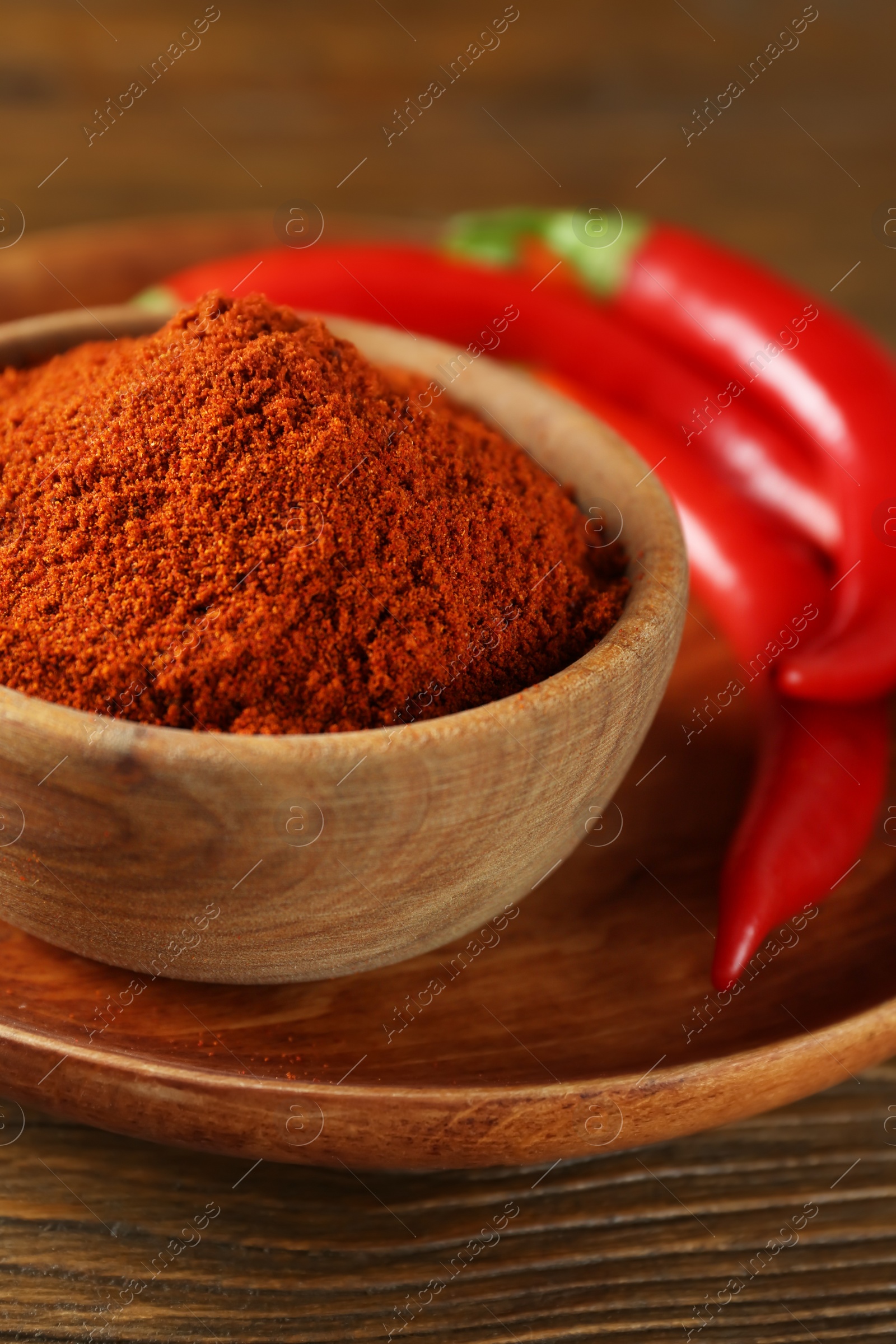 Photo of Paprika powder and fresh chili peppers on wooden table, closeup