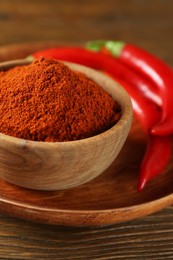 Photo of Paprika powder and fresh chili peppers on wooden table, closeup