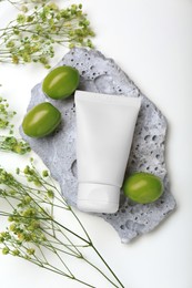 Photo of Tube of cream, olives and flowers on white background, flat lay