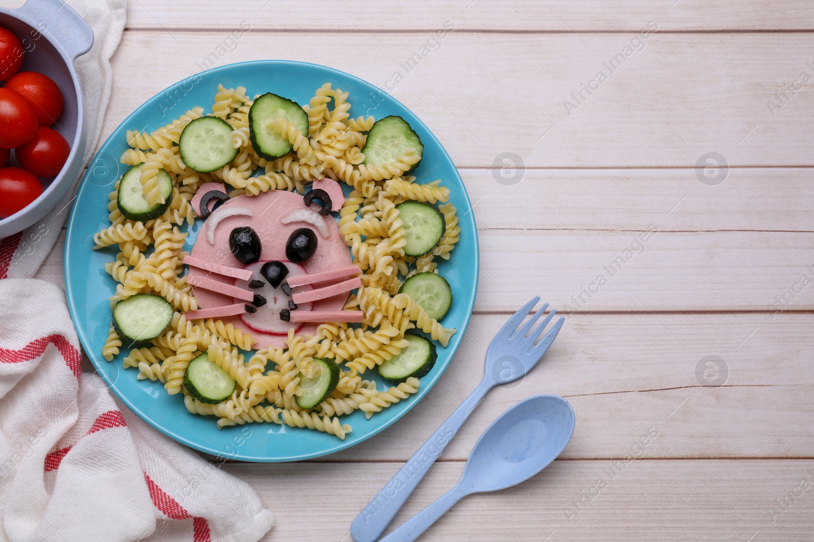 Photo of Creative serving for kids. Plate with cute bear made of tasty pasta, vegetables and sausage on white wooden table, flat lay. Space for text