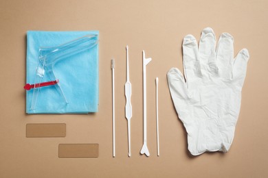 Photo of gynecological examination kit on light brown background, flat lay