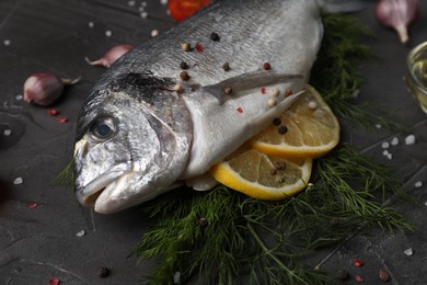 Photo of Fresh dorado fish with lemon, dill and spices on grey table, closeup