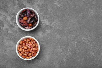Photo of Bowls with different types of beans on grey table, flat lay. Space for text