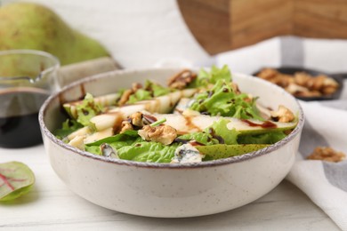 Photo of Delicious pear salad with sauce in bowl on white wooden table, closeup