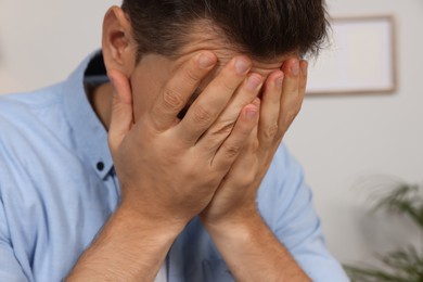 Photo of Sad man closing his face with hands indoors, closeup