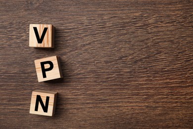 Photo of Cubes with acronym VPN on wooden table, flat lay. Space for text