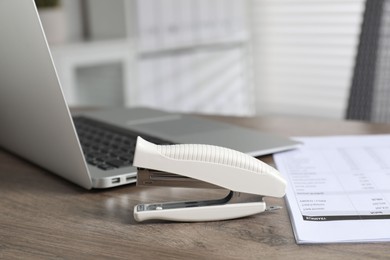 Photo of Stapler and document on wooden table indoors, closeup